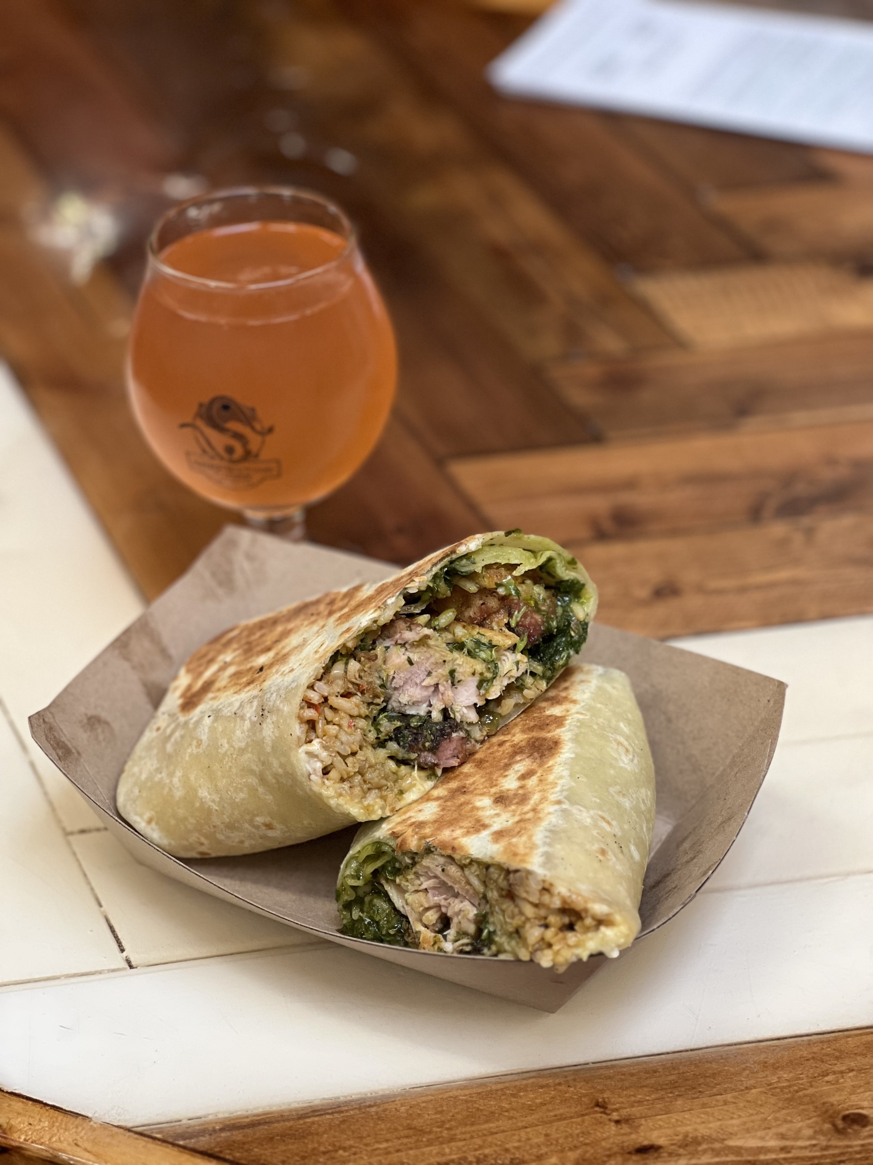 A poured glass of Serpentine cider alongside a hearty burrito — showcasing food-friendly cider flavors.